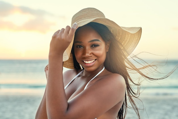 Protecting herself from the suns rays Shot of a beautiful young woman in a bikini on the beach