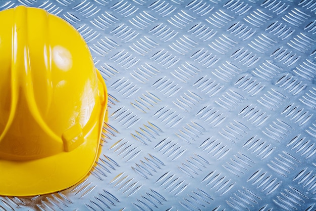 Protective building helmet on chequered metal sheet copy space construction concept