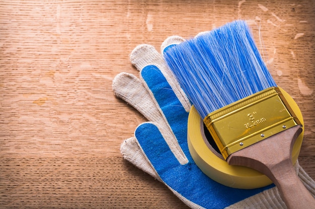 Protective gloves paint brush and duct tape on wooden board construction concept