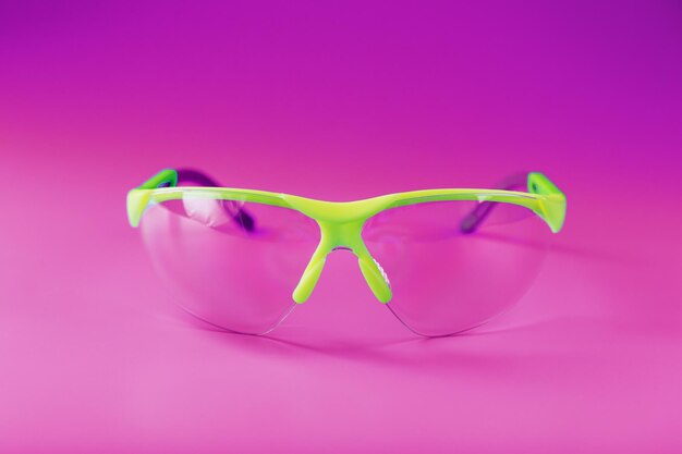 Protective open glasses isolated on a pink background. Reliable eye protection, free space