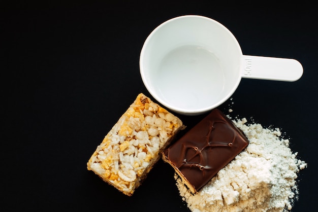 Protein powder and energy bars on a black wall