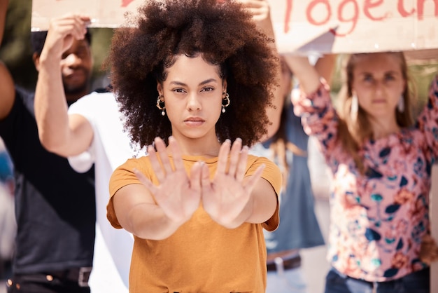 Protest hands and stop with a black woman activist in demonstration with a group of people ready to fight for freedom Community politics and rally with a young female standing against violence