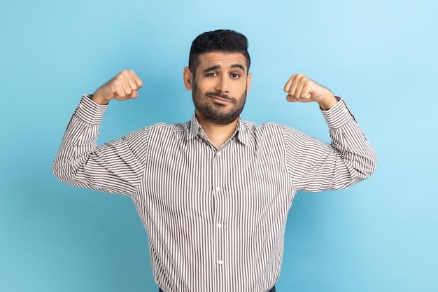 Proud businessman demonstrating power in his hands showing biceps feeling energy to win success