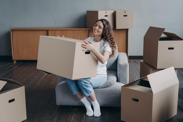 Proud european girl relocates to new home Happy young woman moves alone