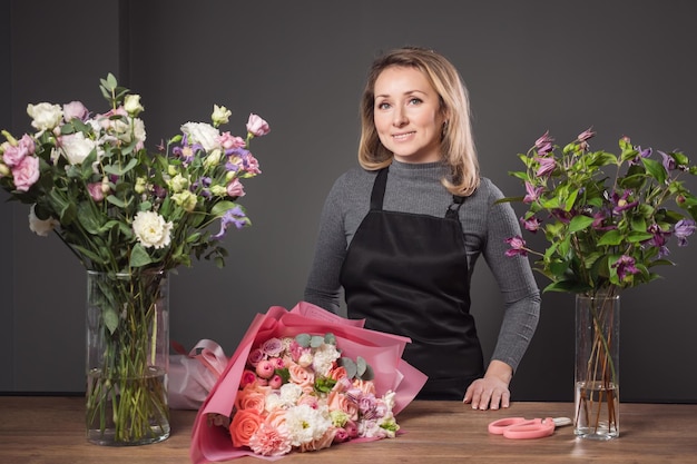 Proud florist blonde woman holds composed flower bouquet