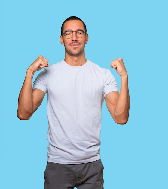 Proud young man doing a gesture of strength with his arm