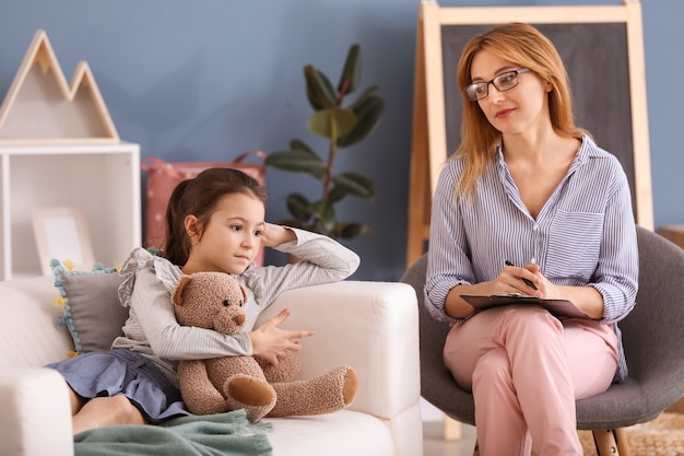 Psychologist working with little girl indoors