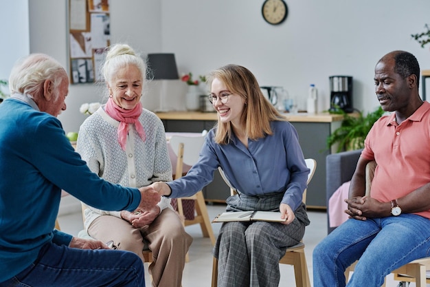 Psychotherapist greeting senior people at therapy