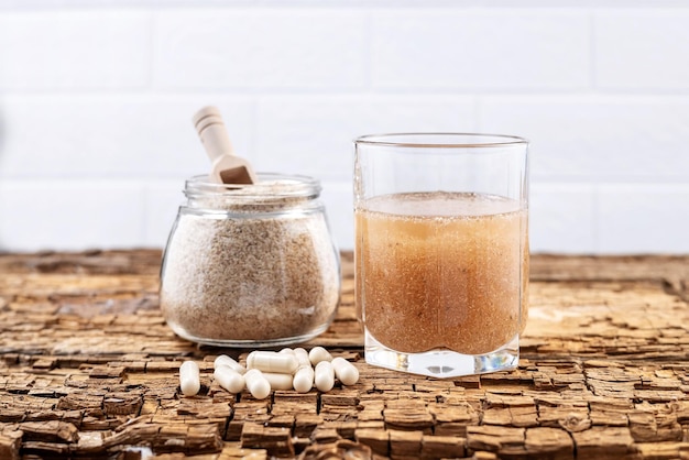 Psyllium capsules and a glass of water and psyllium husk on an old wooden board