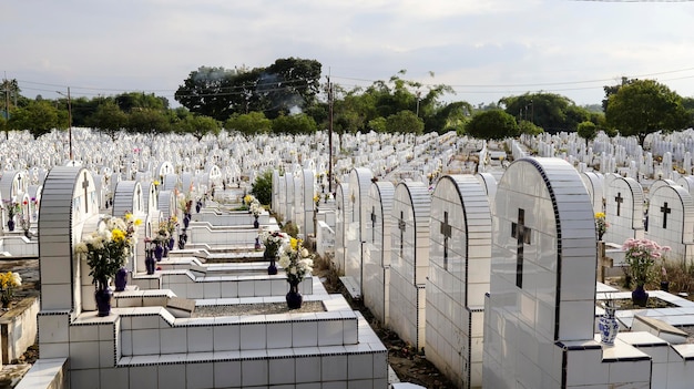 The public cemetery contains identical white ceramic graves with flowers