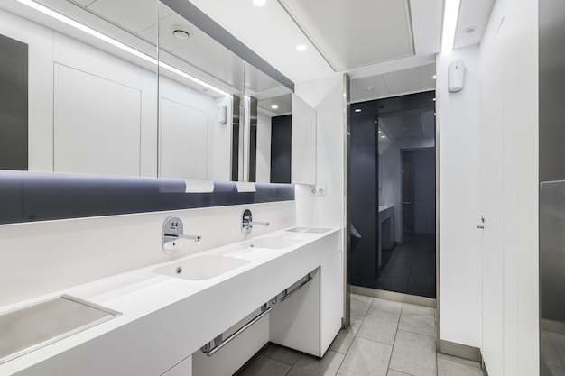 Public or office interior of male restroom with sinks and big mirror modern design bathroom in white...