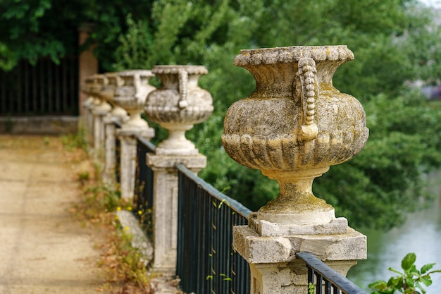 Public park walk along the Tagus river and iron fence with ancient stone vases