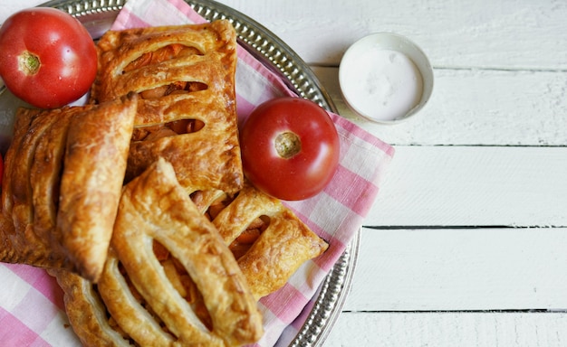 Puff pastry with tomato on a white wooden table with copy space