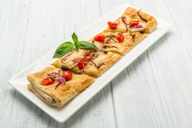 Puff-pizzas with mozzarella cheese, cherry tomatoes and baby basil.