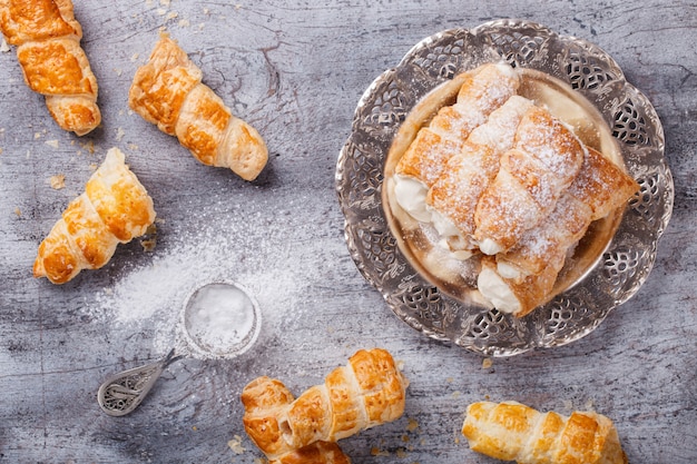 Puff rolls with cream on vintage metal plate.