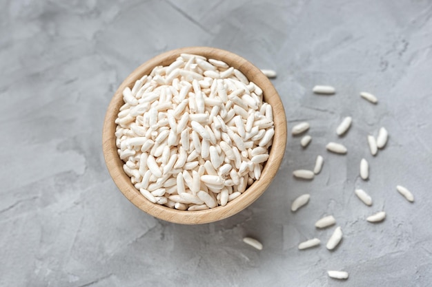 Puffed rice in a wooden bowl on a gray background concept of healthy eating vegan food Close up selective focus copy space