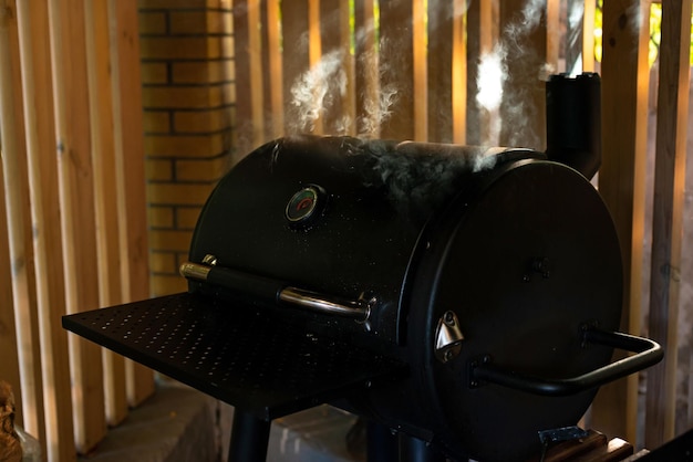 Puffs of thick smoke rising from a closed barbecue grill. Summer outdoor recreation. Soft selective focus.