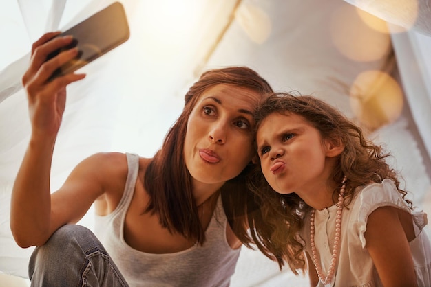 Pull a funny face Shot of a mother and daughter having fun and taking a photo together while pulling a face