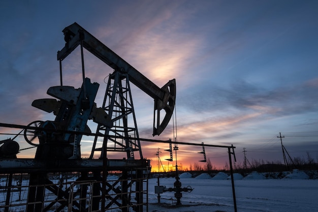 Pump jack at sunset sky background. Extraction of oil. Petroleum concept.