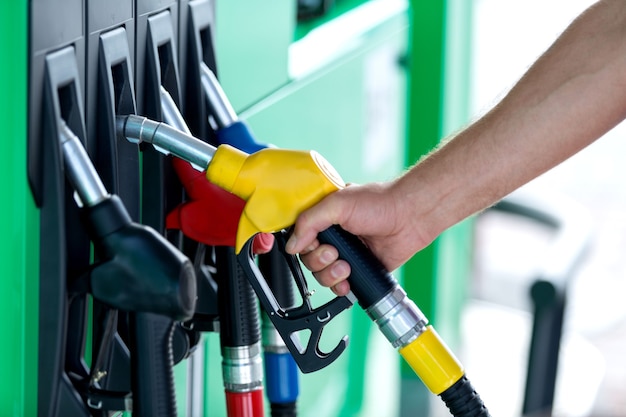 Pumping gas at gas pump. Closeup of man pumping gasoline fuel in car at gas station.