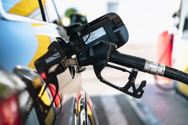 Pumping gasoline fuel in brown car at gas station