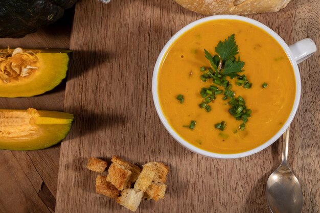 Photo pumpkin broth on wooden background.