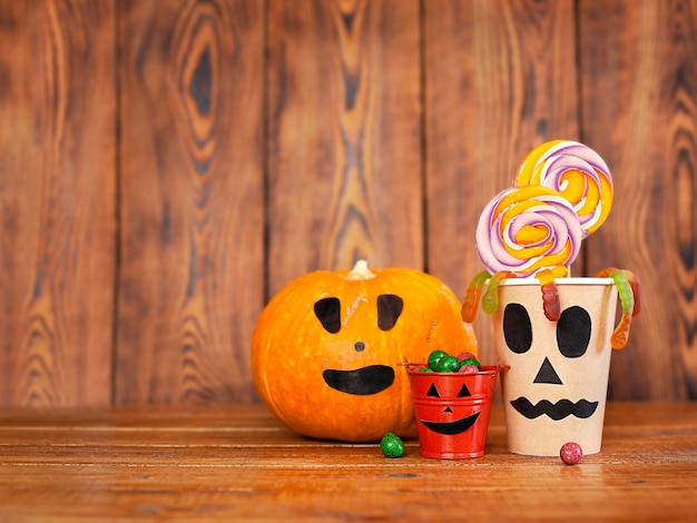 pumpkin and buckets with sweets on a wooden background close-up