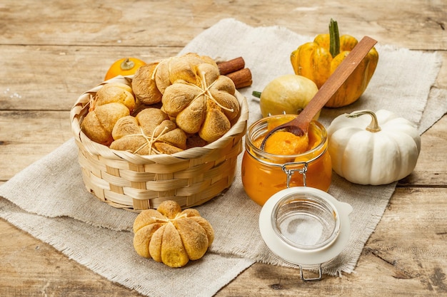 Pumpkin buns or biscuits, traditional fall baked goods. Seasonal homemade food and autumn decor. Old wooden boards background, close up