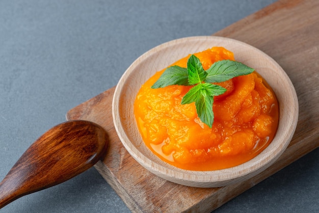 Pumpkin and carrot baby puree in round dish isolated on grey background