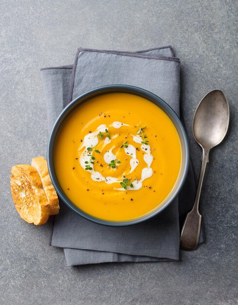 Photo pumpkin carrot cream soup in a bowl grey background top view