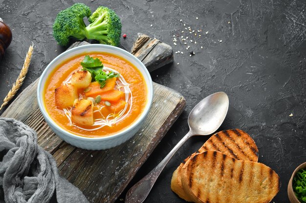 Pumpkin cream soup in a bowl with toast bread Dietary food Top view Free copy space