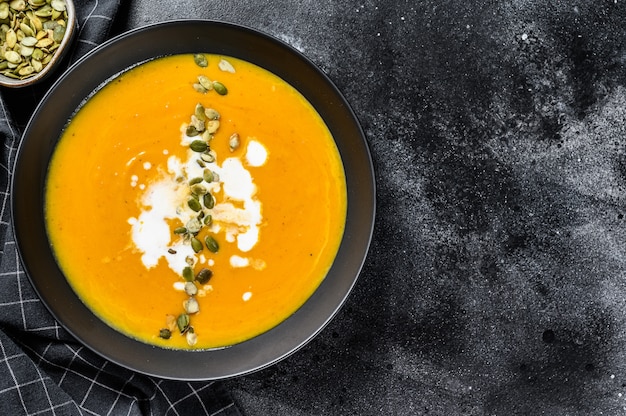 Pumpkin cream soup with cream and pumpkin seeds. Top view. Copy space