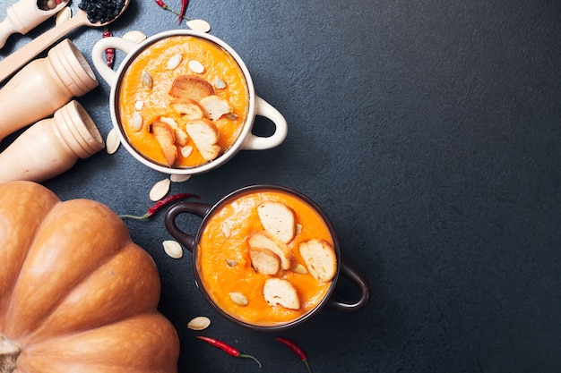 Pumpkin cream soup with croutons on a black table with spices. High quality photo