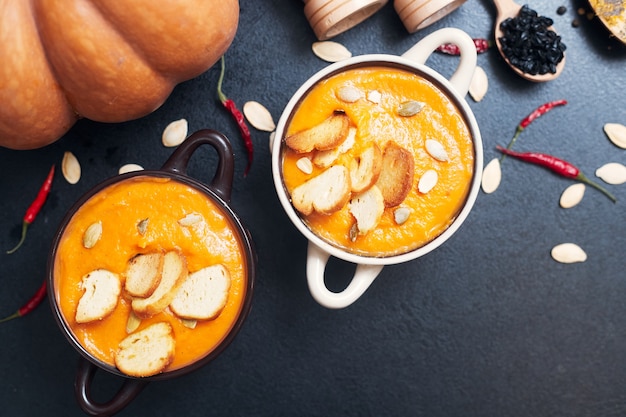 Pumpkin cream soup with croutons on a black table with spices. High quality photo