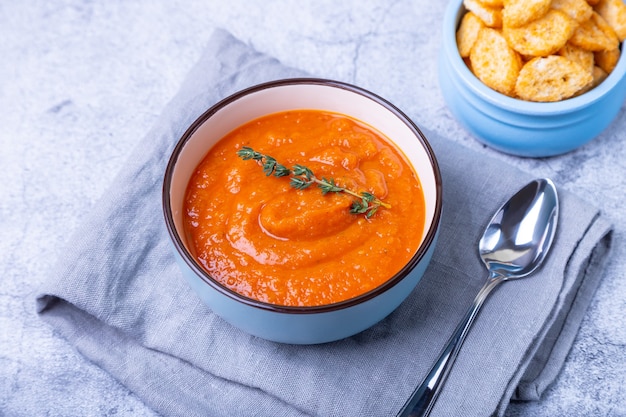 Pumpkin cream soup with croutons and thyme in a bowl