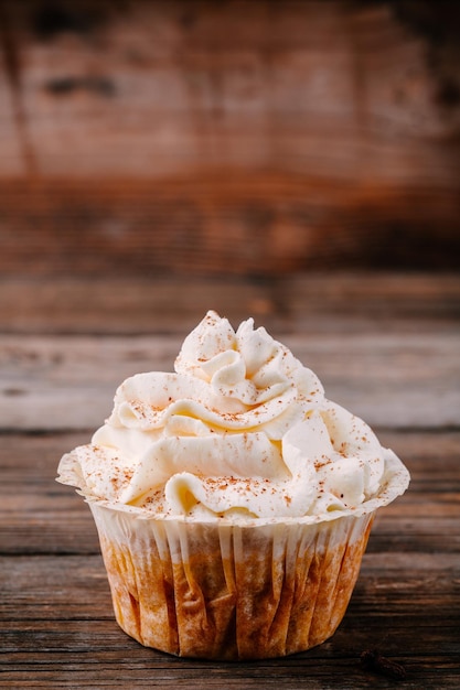 Pumpkin cupcakes decorated with cream cheese frosting on wooden background