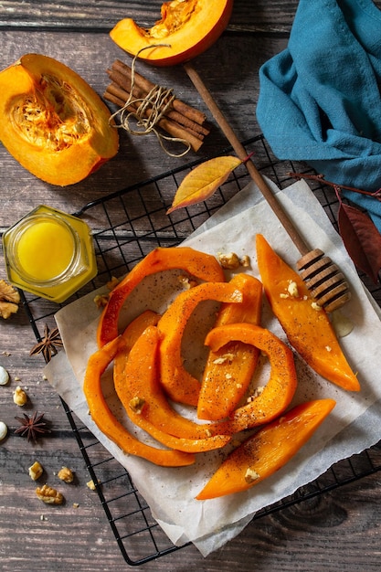 Pumpkin dessert Baked pumpkin slices with honey cinnamon and walnuts on a rustic table Top view