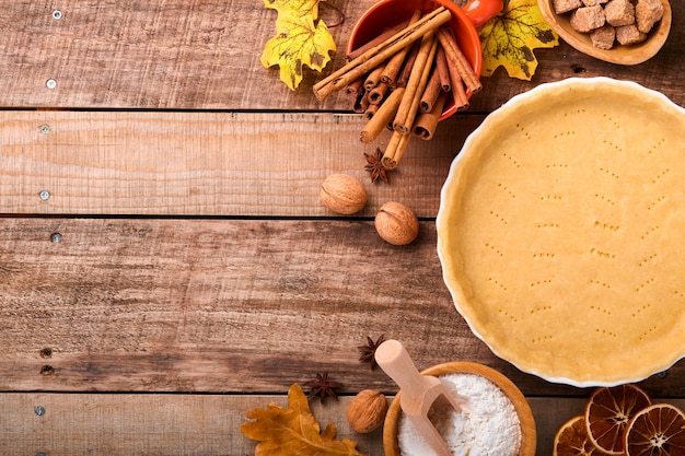 Pumpkin and food ingredients, spices, cinnamon and kitchen utencil on old rustic wooden background. Concept homemade baking for holiday. Cooking pumpkin pie and cookies for Thanksgiving day.