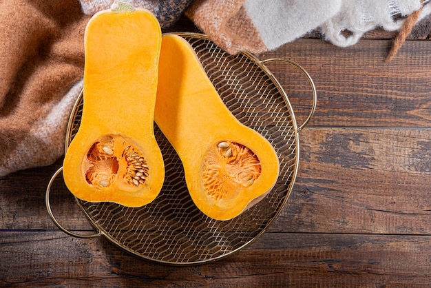 Pumpkin halves on metal gold tray on wooden table autumn harvest