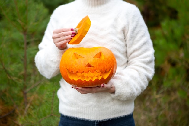 Pumpkin jackolantern in the hands of a girl closeup Halloween party