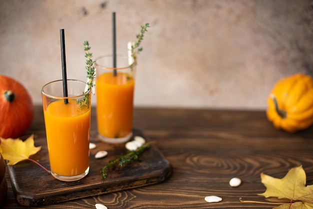 Pumpkin juice in a bottle and glass on a wooden table