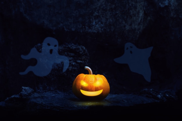 Pumpkin lantern and ghost in a graveyard at night