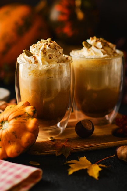 Pumpkin latte with whipped cream in a glasses in the style of dark food. Autumn Hot spicy drink for