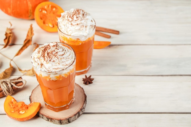 Pumpkin latte with whipped cream on light wooden background Hot spicy smoothie Vegetable vegan drink