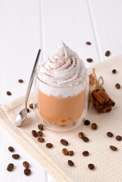 Pumpkin latte with whipped cream and spices on white wooden table