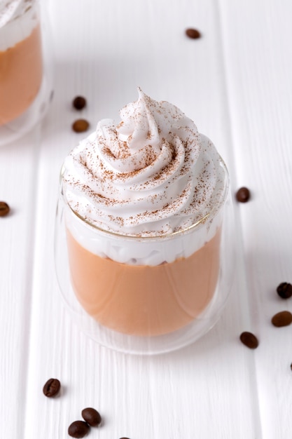 Pumpkin latte with whipped cream and spices on white wooden table