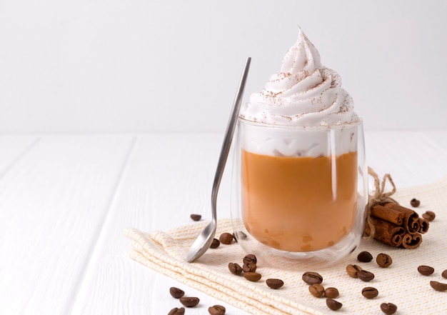 Pumpkin latte with whipped cream and spices on white wooden table