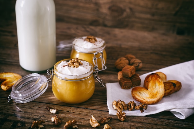 Pumpkin milkshake in glass jar with whipped cream, toffee, walnut and honey cookies