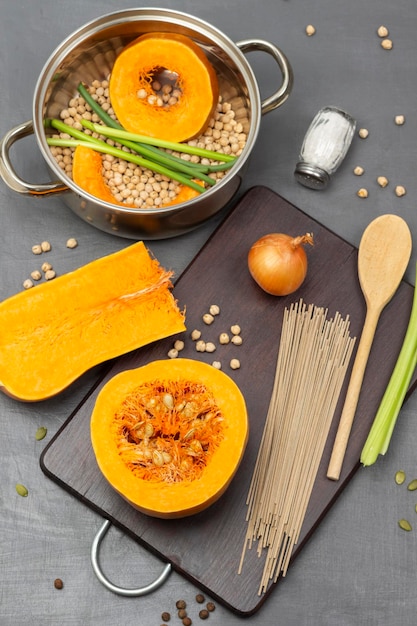 Pumpkin and noodles wooden spoon and onion on cutting board