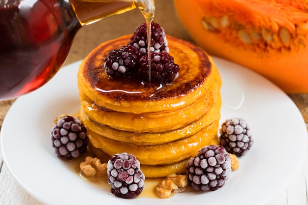 Pumpkin pancakes with maple syrup, berries and nuts. End of seasonal (autumn) breakfast.